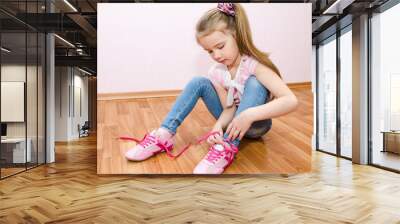 cute smiling little girl tying her shoes Wall mural