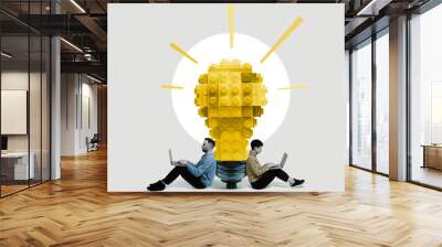 A man and a woman with laptops sit near a large light bulb made of blocks. Art collage. Wall mural