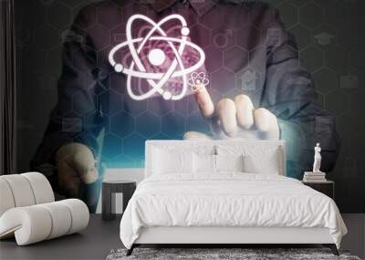 Concept of scientific and educational online service. Person touches to the atom icon.  He holds tablet pc, that contains a many different online services. Wall mural