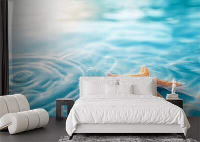 Summer background. One red starfish lies on the blue water surface Wall mural