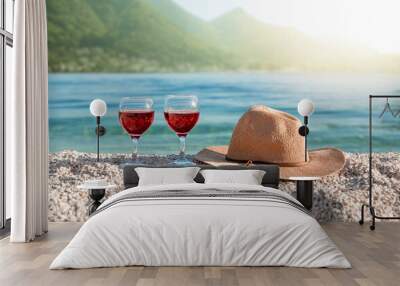 Two glasses with red wine and a straw hat on the Kotor Bay Montenegro beach. Mountain View Wall mural