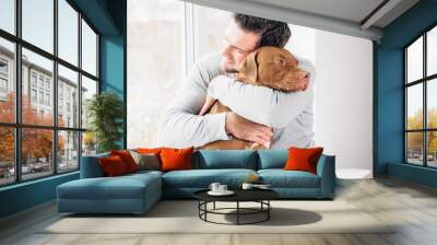 Adorable man and lovable, pretty puppy of brown color. Close-up, indoor. Day light. Concept of care, education, obedience training and raising pets Wall mural