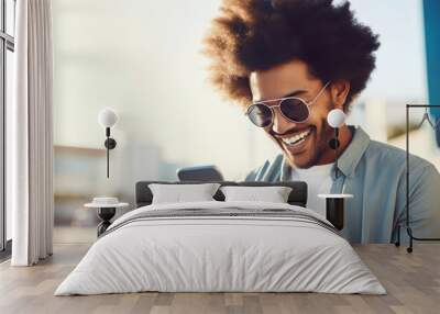 An young man with huge afro looking at the smartphone and laughing closeup. Wall mural