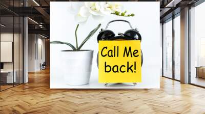 call me BACK! text on yellow sticker prekpelen alarm clock near green orchid plant on white background Wall mural