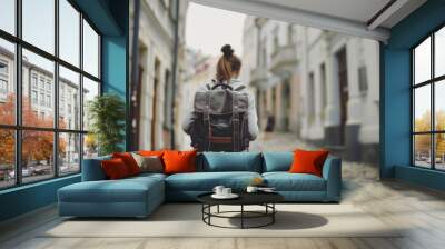 Caucasian woman exploring historic streets with a travel backpack during her solo vacation adventure Wall mural