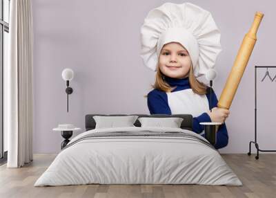 Children cook. Happy little girl in chef uniform holds rolling pin isolated on white background Wall mural