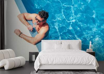 Fashionable man sitting by the pool on the empty deck of a cruise liner. Closeup, outdoor, view from above. Vacation and travel concept Wall mural