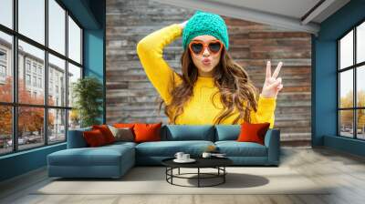 Beautiful brunette woman in sunglasses and knitted  cap blowing Wall mural