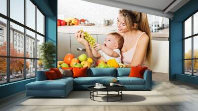 Happy young mother with a baby in the kitchen interior. Fresh ve Wall mural