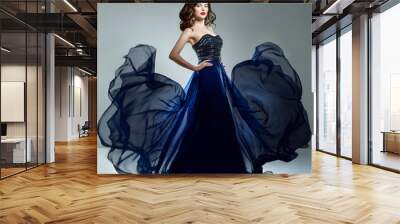 Woman in blue evening dress flying on wind. Young beauty woman i Wall mural