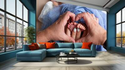 feet of a newborn baby in the hands of parents. legs on a blue background. baby feet Wall mural