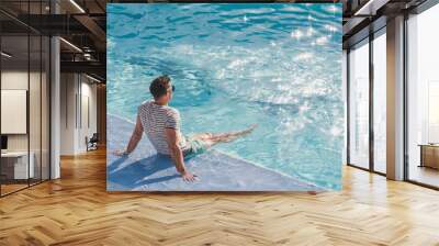 Handsome man sitting near the swimming pool of a cruise ship. Sunny morning, clear day. View from above. Closeup, outdoors. Vacation and travel concept Wall mural