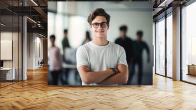 happy european high school student guy standing in classroom with arms crossed. Wall mural