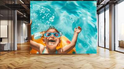 happy little girl wearing swimming goggles and an inflatable ring is playing in the pool on a sunny day. closeup shot of the smiling expressions of children holding toys on their backs, natural light Wall mural