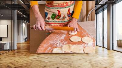 A woman turns dough balls into flat cakes with a rolling pin. Homemade baking Wall mural