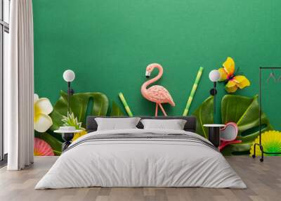 Exotic tropical summer background. Summer beach party concept. Pink flamingo, tropical leaves, orchid flowers and other accessories on green background. Flat lay, copy space. Wall mural