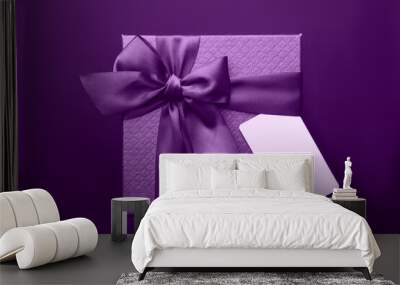 A purple gift box with a tag on the black background. Wall mural