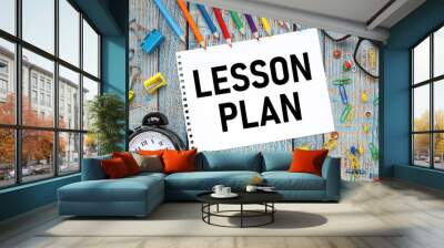 Lesson Planning text on paper from a notepad on a blue wooden background near orange blue and other colors of pencil straps and black glasses. Wall mural