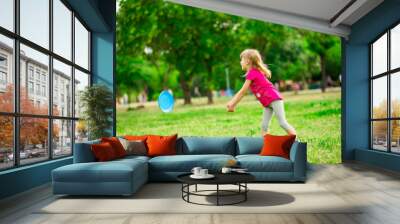 Little girl play with flying disk in motion, playing leisure activity games in summer park Wall mural