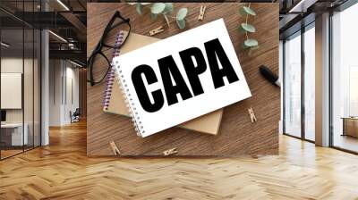 on a wooden background there are two notepads near glasses and a black felt-tip pen. Support Local. CAPA Corrective and Preventive action plans Wall mural