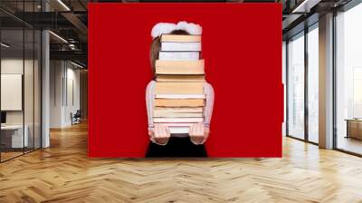 Portrait of cheerful little girl isolated on red hold many books. Concept of knowledge or school. Book lover. Wall mural