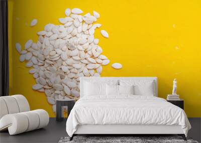 Pumpkin seeds on yellow background. Space for text Wall mural