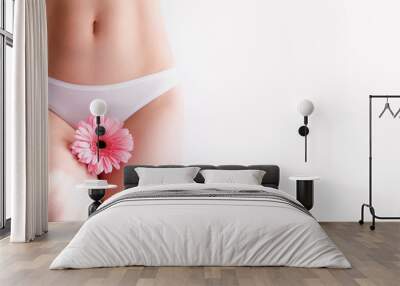 slim woman dressed in white panties, holding a pink flower in her hands. Gynecology, menstruation, the concept of woman genital health. Wall mural