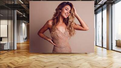 Gorgeous  seductive woman with blonde wavy hairs posing in studio. wearing elegant beige sequins  dress. Space for text. Beige background. Wall mural