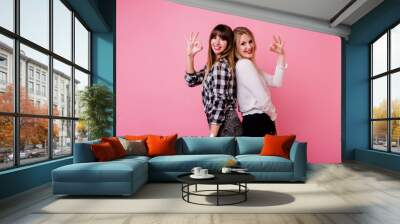 Great team, two successful colleagues  posing over pink background and  showing signs. Wall mural