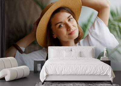 Indoor close up portrait of elegant pretty woman in straw hat and white dress  posing at home. Wall mural