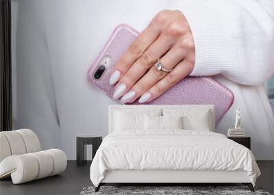 the female hands engagement ring in the sweater is holding a  smartphone in glitter case. A beautiful professional manicure with nude wedding design Wall mural