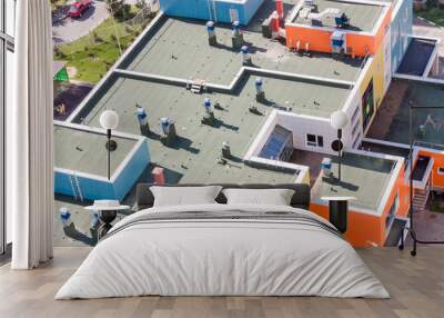 Top view flat roof with air conditioners and hydro insulation membranes on top of a modern blue and orange apartment building sunny summer day. Wall mural