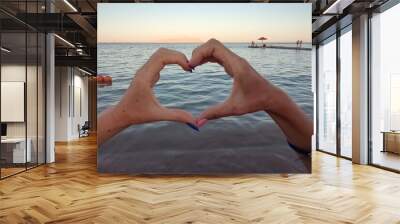 two hands in the shape of a heart on the background of the sea Wall mural