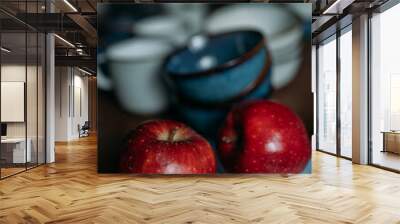 Two red ripe apples on a blue chopping board. There are grey and blue dishes in the background. A set of dishes for lunch. Dinner set for the whole family Wall mural