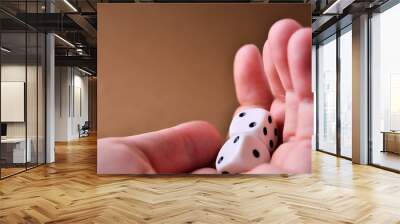 White dice lie in the palm of your hand close up on a brown background with a copy space. High quality photo Wall mural