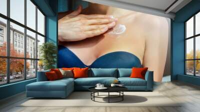 Woman applying moisturizing cream on chest Wall mural