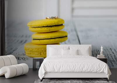 Yellow tasty french macarons and engagement ring on white wooden table. Marry me Wall mural