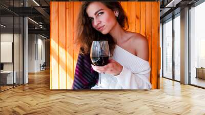 young beautiful woman in a white sweater and gray knee socks drinking red wine on a wooden background Wall mural