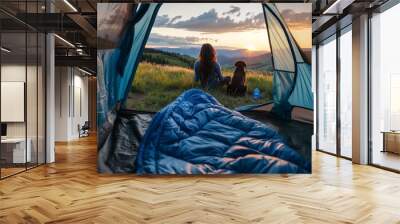 Young woman sitting in a tent with a sleeping bag and dog watching the view of a valley at sunset. Vibrant color photography. Wide angle lens. Beautiful The photo was taken from behind the girl's head Wall mural