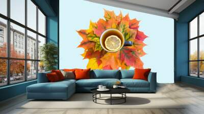 Autumn hot tea with lemon over colorful leaves on blue background. Healthy season beverage. Top view. Wall mural