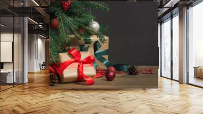 Christmas holiday background. Gifts with a red ribbon, Santa's hat and decor under a Christmas tree on a wooden board. Close up. Copy space on chalkboard. Wall mural