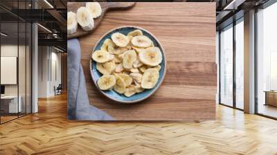 Dehydrated, dried banana chips on wooden board. View from above. Wall mural