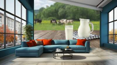 Fresh milk in glass on dark wooden table and blurred landscape with cow on meadow. Healthy eating. Rustic style. Wall mural