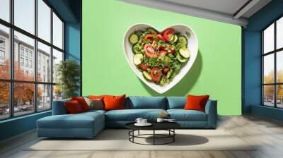 Fresh salad with tomato, cucumber, vegetables, microgreen radishes in plate shape of heart on green. View from above. Concept vegan and healthy eating. Wall mural