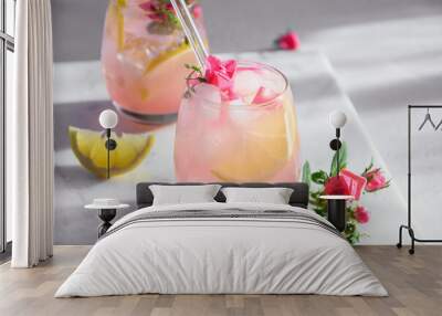 Freshness pink lemonade with rose gin garnish lemon in sunny shadow on white background. Close up. Wall mural