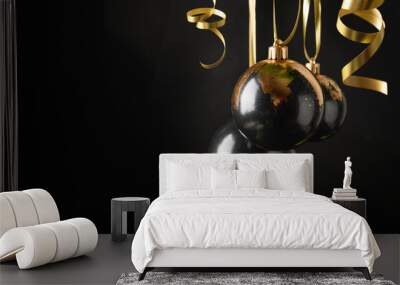 Three gold decoration Christmas balls hanging isolated on black background. Close up. Xmas holiday decoration and greeting card. Wall mural