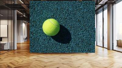 Yellow tennis ball with sunny shadow on blue tennis court with artificial covering. View from above. Summer sports. Wall mural