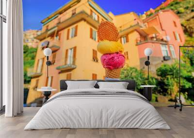 Hand with gelato and view of traditional houses in Manarola, Cinque Terre, Italy Wall mural