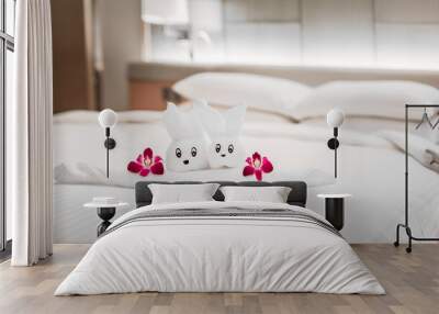 Hotel bed with towel art design shaped as a bear in a flower basket with orchids Wall mural