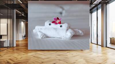 Hotel bed with towel art design shaped as a bear in a flower basket with orchids Wall mural